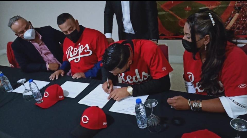 Venezuelan shortstop Ricardo Cabrera, second from right, signs his contract with the Cincinnati Reds on Jan. 15, 2022.