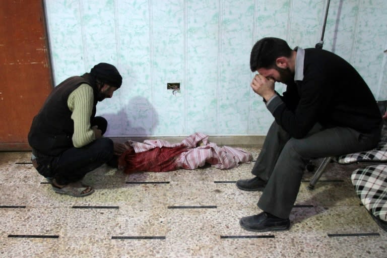 Syrian men mourn over the body of a child at a makeshift clinic following reported shelling by Syrian government forces, in the rebel-held town of Douma in Syria's eastern Ghouta region, on November 19, 2017