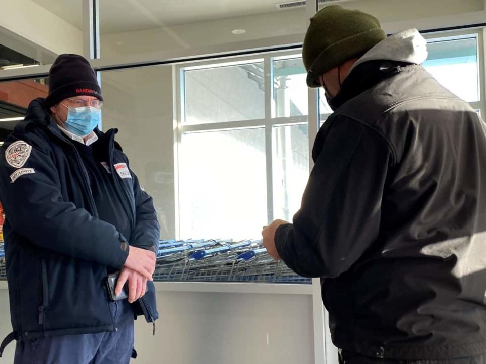 A security guard waits to scan a man's vaccine passport in Quebec City. Starting Monday, Jan. 24, retail stores that with a surface area of 1,500 square meters or more. (Hadi-Hassin/Radio-Canada - image credit)