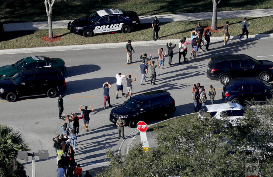 <p>Students hold their hands in the air as they are evacuated by police from Marjory Stoneman Douglas High School in Parkland, Florida, after a shooter opened fire on the campus. (Mike Stocker/South Florida Sun-Sentinel via AP) </p>