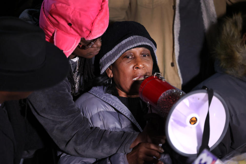 RowVaughn Wells, in a quilted jacket and winter hat, speaks, holding a megaphone.