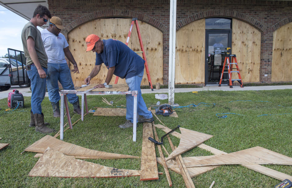 Bernie Arnould, center, gets help from Kaden Ashley and D.J. Hebert, left, all with Pelican Companies, as they board up the windows to the front of MC Bank in Amelia, La., Wednesday, Oct., 7, 2020, in In preparation for Hurricane Delta. (Chris Granger/The Times-Picayune/The New Orleans Advocate via AP)