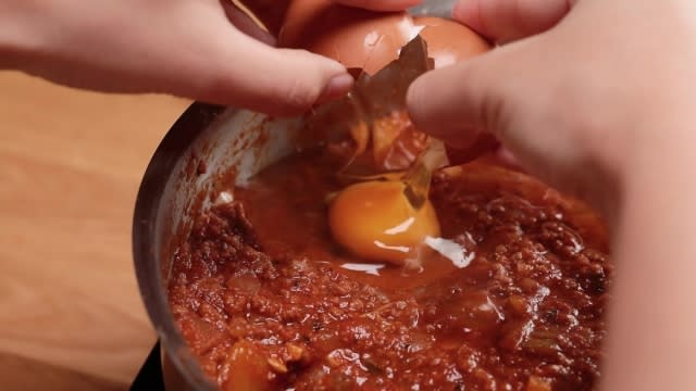 Cracking egg into "wells" of Shakshuka 