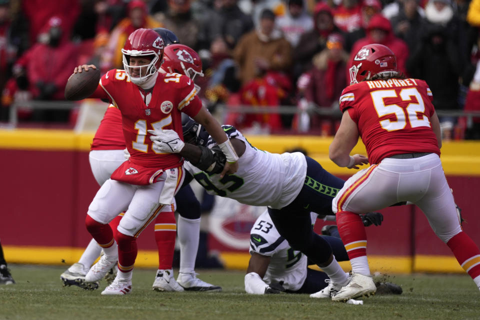 Kansas City Chiefs quarterback Patrick Mahomes (15) slips away from Seattle Seahawks defensive end Shelby Harris (93) during the second half of an NFL football game Saturday, Dec. 24, 2022, in Kansas City, Mo. (AP Photo/Charlie Riedel)