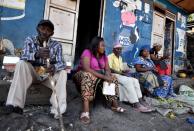 Traders sit near a deserted crossing point between the Democratic Republic of Congo and Rwanda amid concerns about the spread of coronavirus disease (COVID-19), at the Petite Barriere in Goma