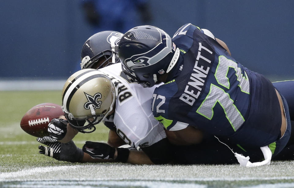 New Orleans Saints quarterback Drew Brees, left, fumbles the ball as he is sacked by Seattle Seahawks defensive end Cliff Avril, hidden, and defensive end Michael Bennett (72) during the third quarter of an NFC divisional playoff NFL football game in Seattle, Saturday, Jan. 11, 2014. The Saints recovered the fumble. (AP Photo/Elaine Thompson)
