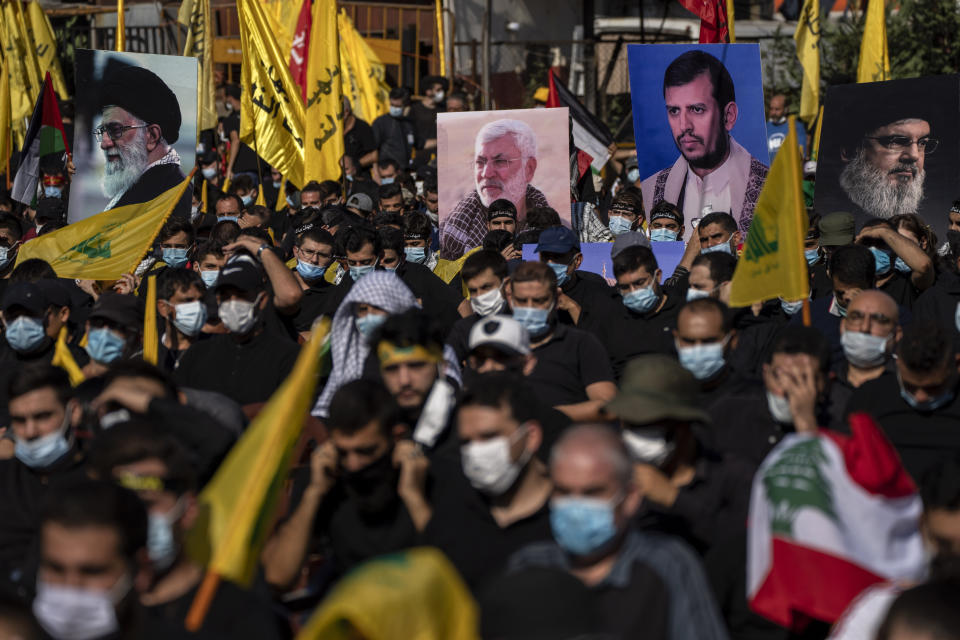 Hezbollah supporters hold up pictures of Supreme Leader Ayatollah Ali Khamenei, left, former Iraq's Popular Mobilization forces commander Abu Mahdi al-Muhandis, second left, Abdel-Malek al-Houthi, the leader of Yemen's Shiite rebels, second right, and Hezbollah leader Sayyed Hassan Nasrallah as they listen to the story of Ashoura, the Shiite Muslim commemoration marking the death of Immam Hussein, the grandson of the Prophet Muhammad, at the Battle of Karbala in present-day Iraq in the 7th century, in southern Beirut, Lebanon, Thursday, Aug. 19, 2021. The leader of the militant Hezbollah group Sayyed Hassan Nasrallah said Thursday that the first Iranian fuel tanker will sail toward Lebanon "within hours" warning Israel and the United States not to intercept it. (AP Photo/ Hassan Ammar)