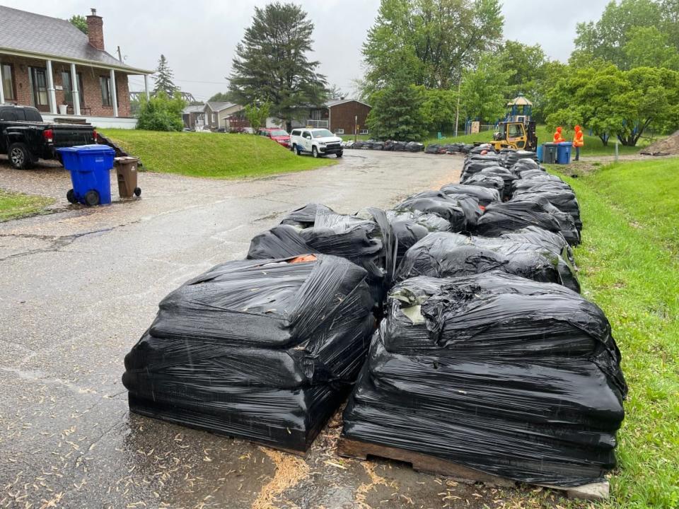 Sandbags are stacked along a street in the Touraine neighbourhood of Gatineau, Que., on May 27, 2022. City officials are urging people to keep their flood preparations in place, even though the risk of local flooding appears to be diminishing. (Patrick Louiseize/Radio-Canada - image credit)