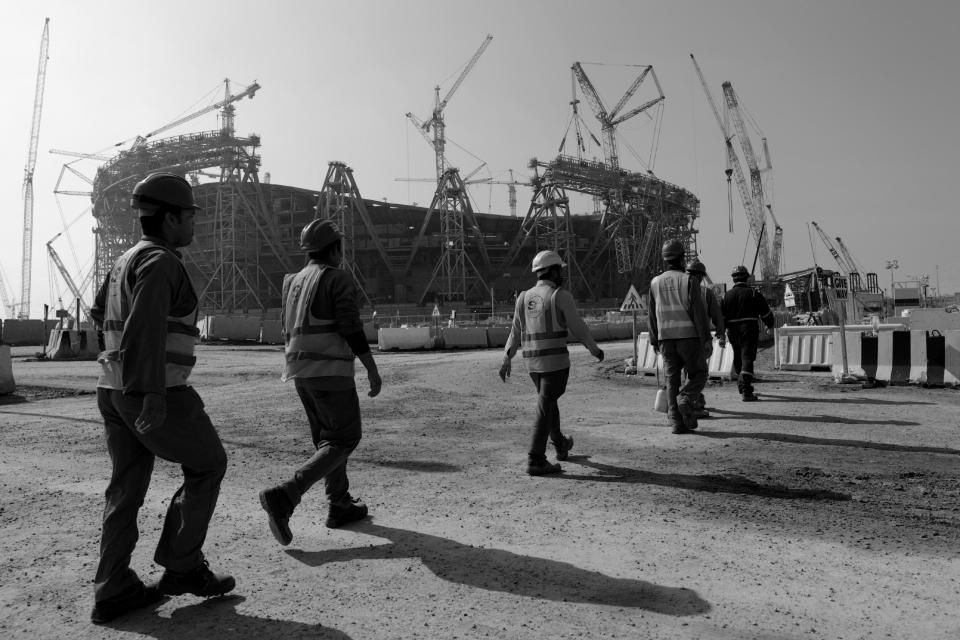 Laborers walk to Lusail Stadium, where the 2022 World Cup final will be held, in Qatar, Friday, Dec. 20, 2019. Migrant workers in Qatar have raised alarms about deceptive pay practices, abuse and poor working conditions, which sometimes led to injury or death.