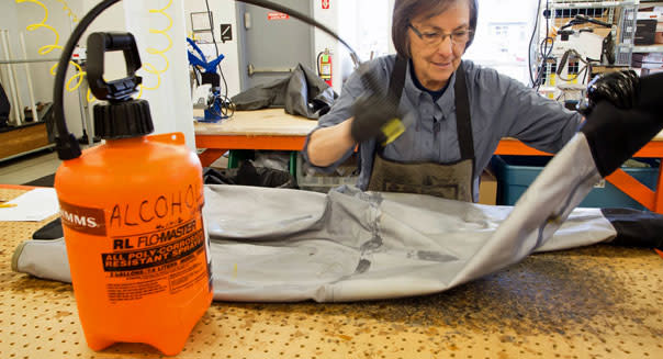 <b class="credit">Devon Riter</b>Simms Fishing Products employee Marie Stull sprays isopropyl alcohol on a pair of waders to test for leaks.