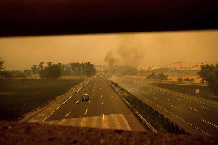 A police vehicle drives along Interstate 80, which was closed when flames from the LNU Lightning Complex fires jumped the roadway, in Vacaville, Calif., on Wednesday, Aug. 19, 2020. Fire crews across the region scrambled to contain dozens of wildfires sparked by lightning strikes. (AP Photo/Noah Berger)