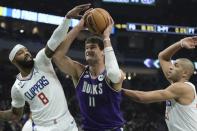 Milwaukee Bucks' Brook Lopez drives between Los Angeles Clippers' Marcus Morris Sr. and Nicolas Batum during the first half of an NBA basketball game Thursday, Feb. 2, 2023, in Milwaukee. (AP Photo/Morry Gash)