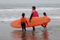 A surf instructor carries a Doyle surfboard in Malibu