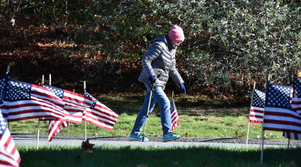 YARMOUTHPORT 11/08/22 Pat Nye makes her way up the hill past a lawn full of flags outside the First Congregational Church in Yarmouthport where voters in precinct one cast their ballots. Cape Cod Times/Steve Heaslip