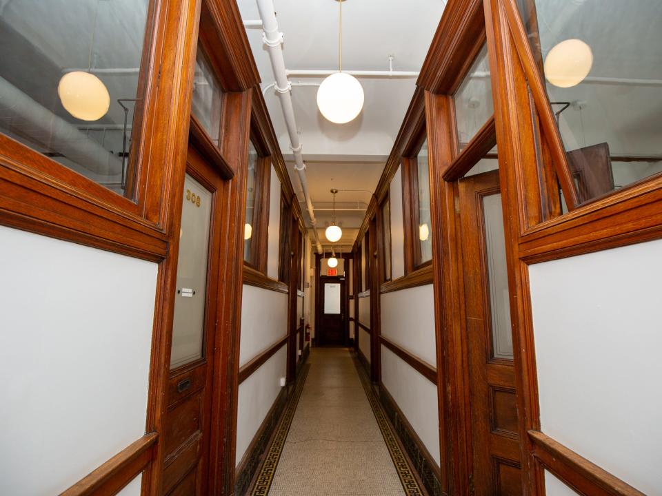 A hallway with white walls, wood accents, lights.