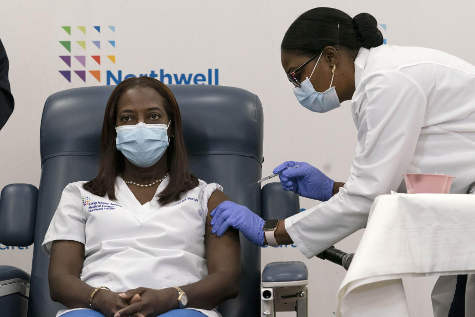 FILE - Sandra Lindsay, left, a nurse at Long Island Jewish Medical Center, is inoculated with the Pfizer COVID-19 vaccine by Dr. Michelle Chester, in the Queens borough of New York, on Dec. 14, 2020. The nation’s COVID-19 death toll stands at around 800,000 as the anniversary of the U.S. vaccine rollout arrives. A year ago it stood at 300,000. What might have been a time to celebrate a scientific achievement is fraught with discord and mourning. (AP Photo/Mark Lennihan, Pool, File)