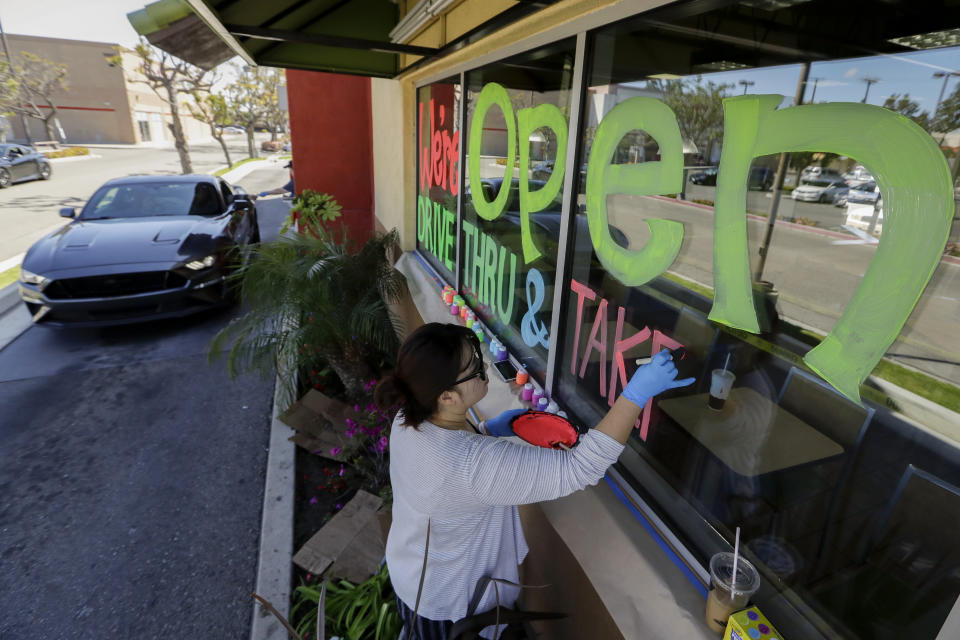 FILE - In this March 26, 2020, file photo, Lucy Kwak paints a sign on the window of a fast food chain's restaurant indicating that the drive-thru window is still open as well as a takeout option during the coronavirus outbreak in Garden Grove, Calif. Taxpayers will pay restaurants to make three meals a day for California's millions of seniors during the coronavirus pandemic, Gov. Gavin Newsom announced Friday, April 24, 2020, putting the industry back to work and generating sales tax collections for cash-strapped local governments. California has about 5.7 million people 65 and older, but not all of them will be eligible, and some will have to meet income thresholds. (AP Photo/Chris Carlson, File)
