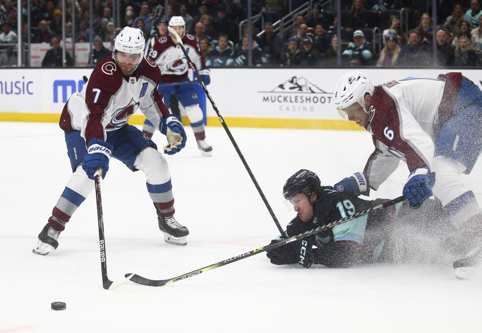 Seattle Kraken left wing Jared McCann (19) falls near the Colorado Avalanche net as Avalanche defensemen Devon Toews (7) and Erik Johnson (6) defend during the second period of an NHL hockey game Saturday, Jan. 21, 2023, in Seattle. (AP Photo/Lindsey Wasson)