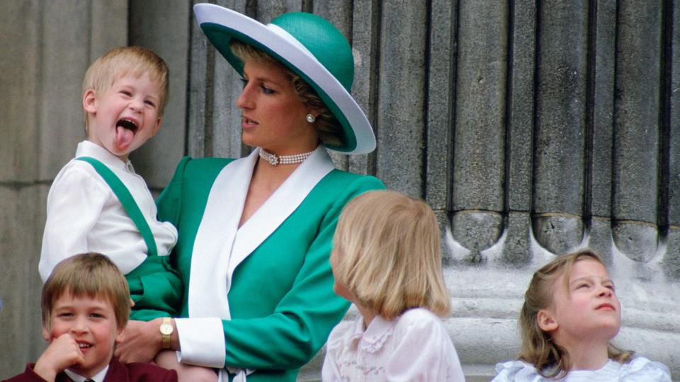 A young Prince Harry sticking his tongue out, while being held by Princess Diana