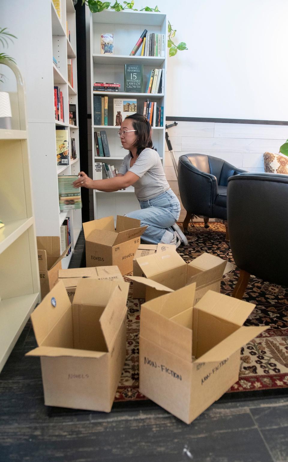 Precious Murphy stocks the bookshelves with reading material at the new Mr. Jones Cold Brew Coffee Bar on Nine Mile Road on Thursday, Sept. 21, 2023. The new coffee shop and bookstore will open to the public on Sept. 28, 2023