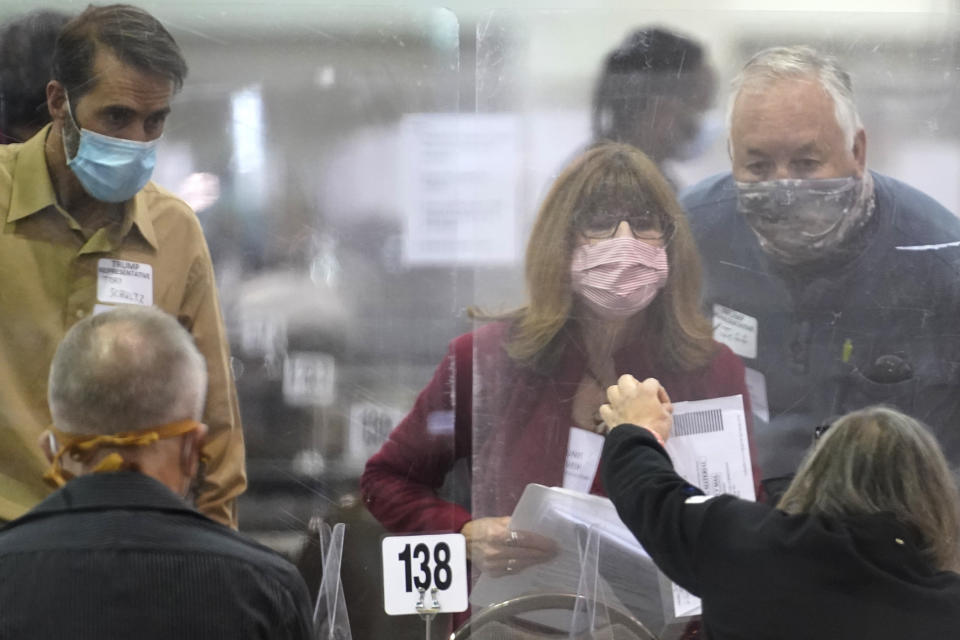 Recount observers check ballots during a Milwaukee hand recount of Presidential votes at the Wisconsin Center, Friday, Nov. 20, 2020, in Milwaukee, Wis. The recount of the presidential election in Wisconsin's two most heavily Democratic counties began Friday with President Donald Trump's campaign seeking to discard tens of thousands of absentee ballots that it alleged should not have been counted. (AP Photo/Nam Y. Huh)