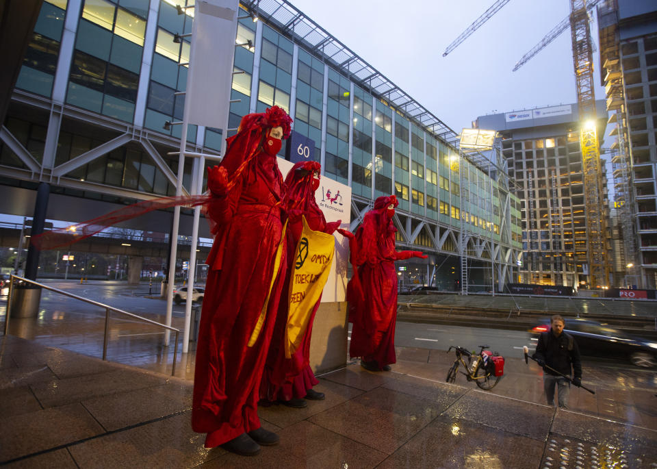 Demonstrators hold a banner reading "standing by and watching is no longer an option" outside the court building prior to the start of the court case of Milieudefensie, the Dutch arm of the Friends of the Earth environmental organization, against Shell in The Hague, Netherlands, Tuesday, Dec. 1, 2020. A landmark legal battle opened as climate change activists in the Netherlands go to court seeking an order for energy giant Shell to rein in its carbon emissions. (AP Photo/Peter Dejong)