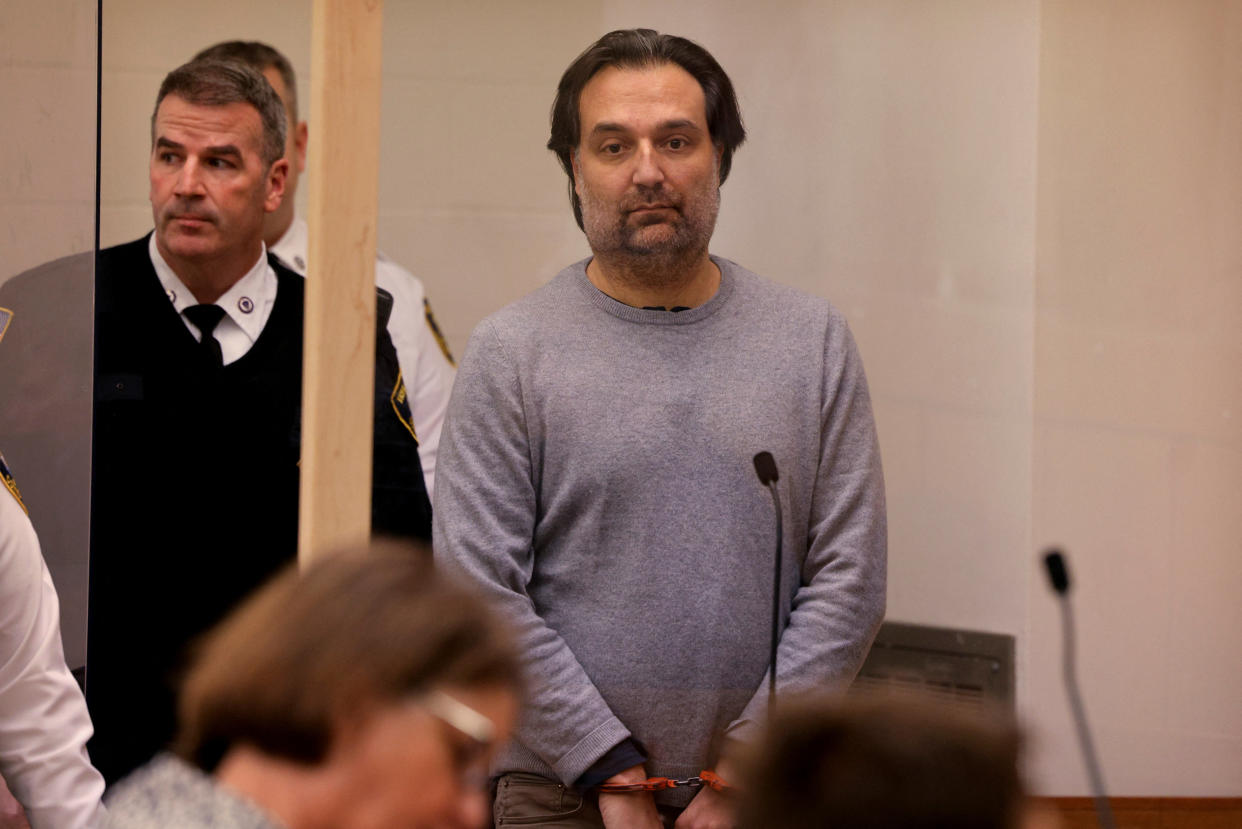 Brian Walshe stands handcuffed in a courtroom.