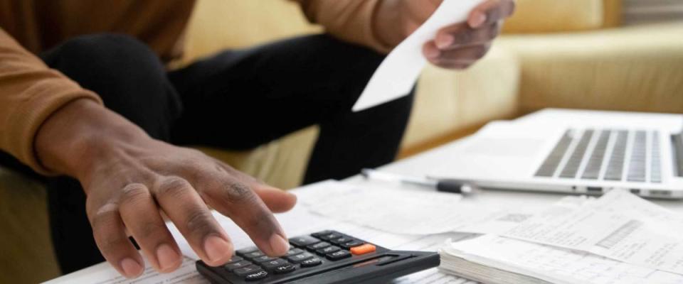 Close up of african American man calculating using machine managing household finances at home, focused biracial male make calculations on calculator paying bills, account taxes or expenses