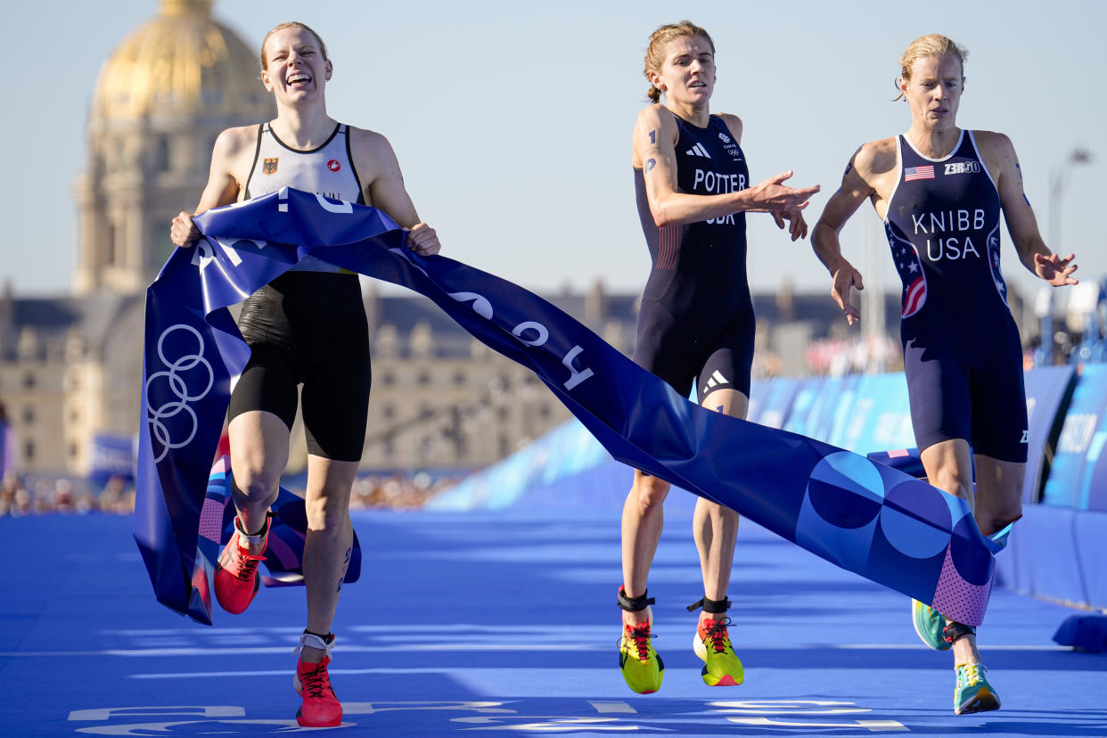 Germany's Laura Lindemann, left, celebrates after winning the gold medal next to silver medalist Britain's Beth Potter, center, and bronze medalist Taylor Knibb, of the United States, right, at end of the mixed relay triathlon at the 2024 Summer Olympics, Monday, Aug. 5, 2024, in Paris, France. (AP Photo/Vadim Ghirda)