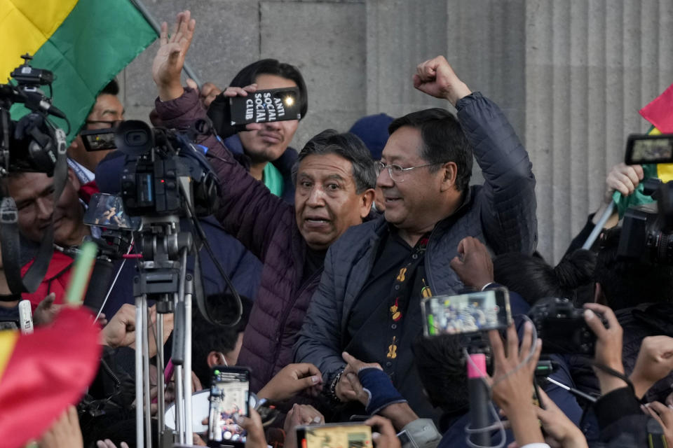 El presidente boliviano, Luis Arce, levanta el puño, junto al vicepresidente, David Choquehuanca, rodeados de seguidores y medios a las puertas del palacio de gobierno en La Paz, Bolivia, el miércoles 26 de junio de 2024. El presidente boliviano denunció un intento de golpe de Estado por parte de soldados que se apostaron frente al palacio de gobierno con vehículos militares blindados. (AP Foto/Juan Karita)