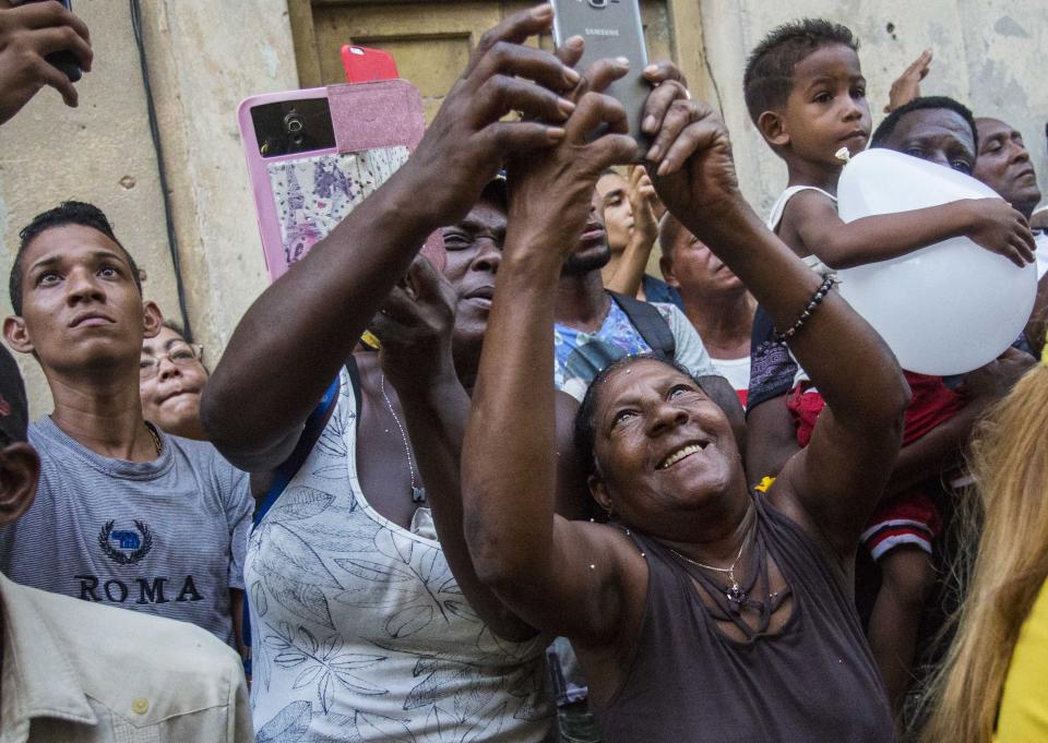 FILE - In this Sept. 8, 2018 file photo, people take pictures of the statue of the Virgin of Charity during an annual religious procession in Havana, Cuba. Cuba's patron saint is also recognized as a powerful deity in the African-influenced religion of Santeria, which refers to her as "Ochun." (AP Photo/Desmond Boylan, File)