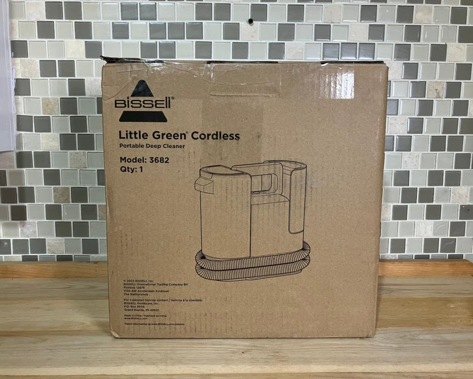 Bissell Little Green Cordless Portable Carpet Cleaner in cardboard box on wooden kitchen worktop with tiled backdrop