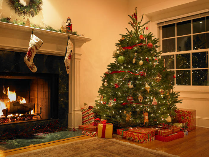 Photo of Christmas tree surrounded by presents and a roaring fire.