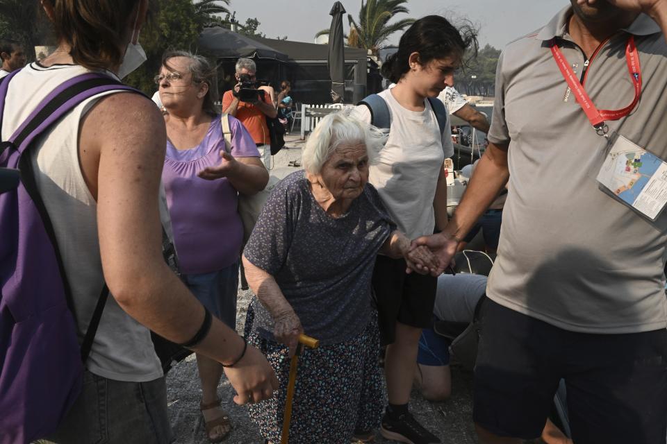 Residents and tourists evacuate with the support of vessels from the town of Nea Anchialos, near Volos city, central Greece, Thursday, July 27, 2023. Wildfires caused explosions at an air force ammunition dump in central Greece on Thursday that had been safely evacuated in advance, as strong gusts of wind caused flare-ups around the country. (Tatiana Bolari/Eurokinissi via AP)