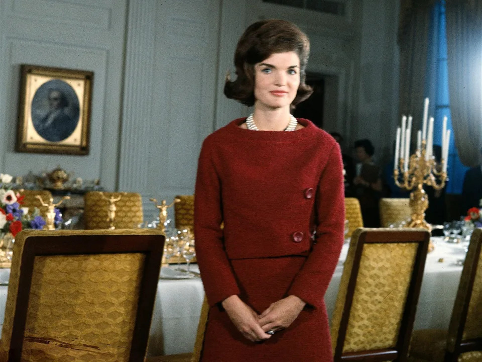 Jackie Kennedy stands in a dining room table inside the White House.