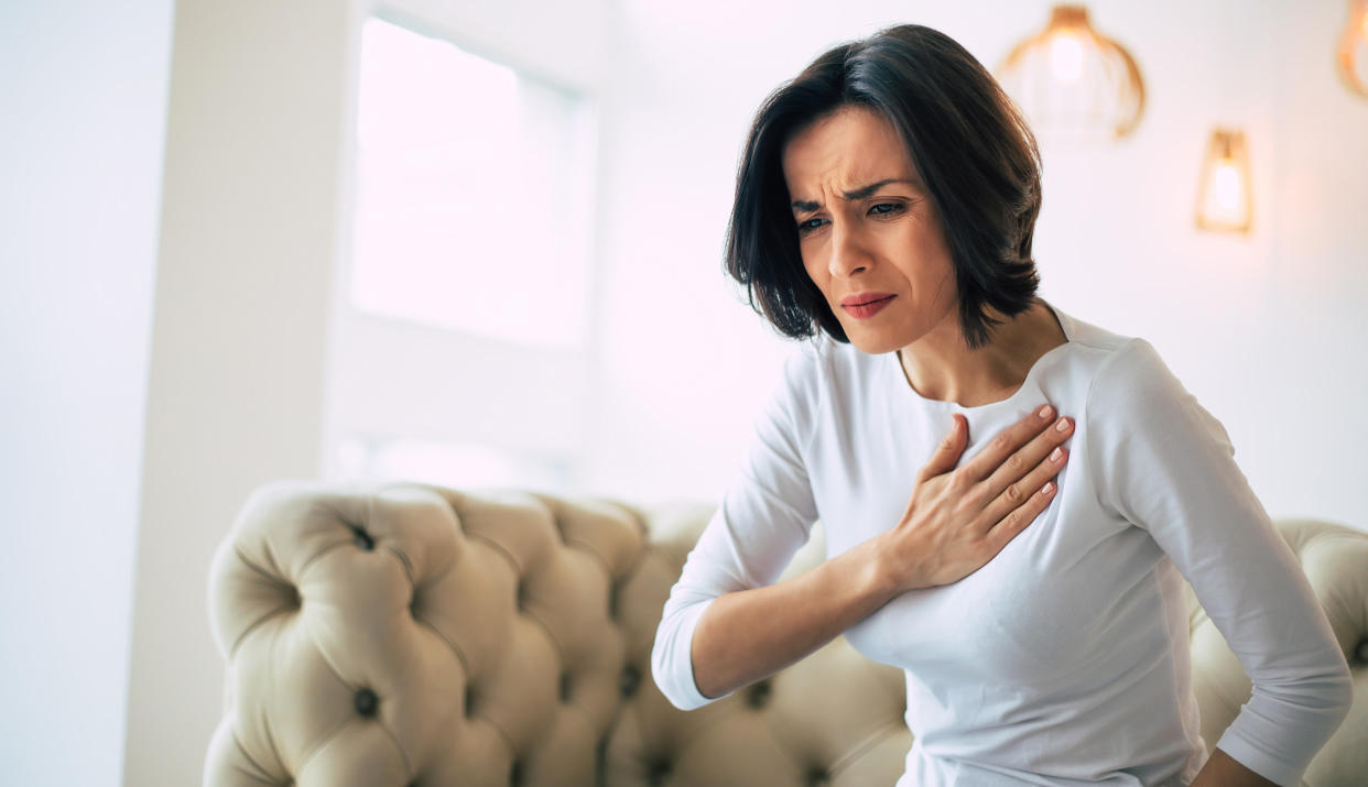 A woman places a hand on her chest.