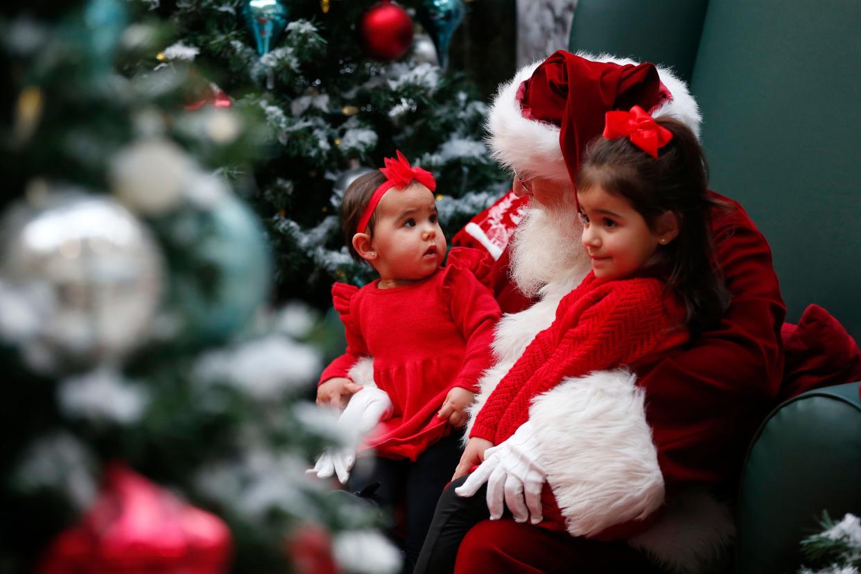 A young girl is not quite sure what she is looking at as she and another girl sit to take a photo with Santa at the Dartmouth Mall.