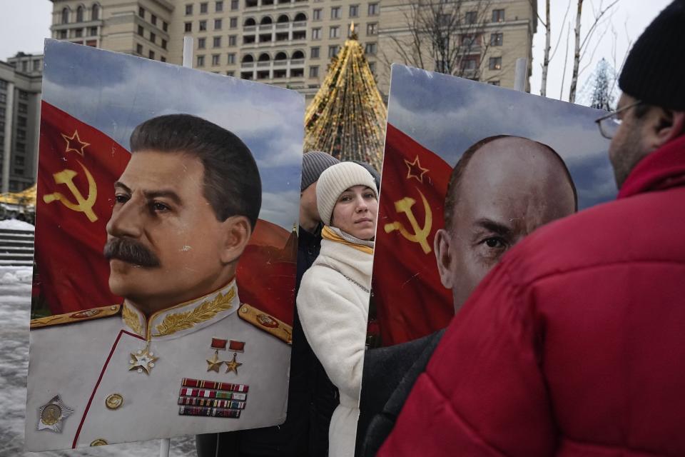 A Communist Party supporter stands between portraits of Soviet leaders Joseph Stalin, left, and Vladimir Lenin on Manezhnaya Square decorated for the New Year and Christmas festivities near the Kremlin Wall in Moscow, Russia, Thursday, Dec. 21, 2023 marking the 144th anniversary of Stalin's birth. (AP Photo/Alexander Zemlianichenko)