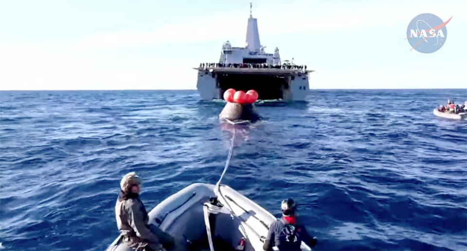 The Orion capsule is towed toward the flooded well deck of the USS Portland, an amphibious transport dock ship. Once inside, the deck will be sealed, the water pumped out and the spacecraft will be left on a protective cradle for the trip back to Naval Base San Diego.  / Credit: NASA