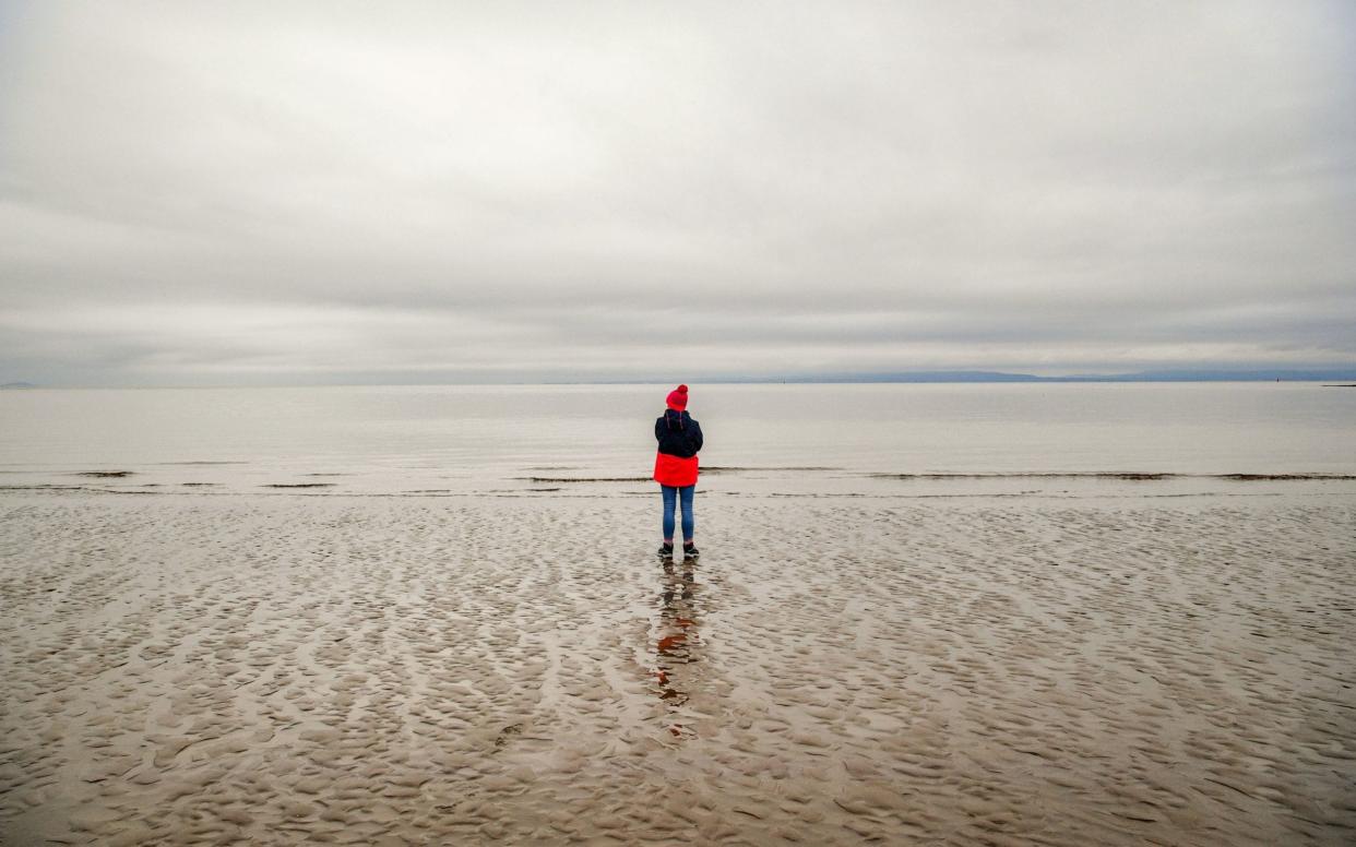 A lone woman at the shoreline on the beach at Barry Island, Wales - Ben Birchall/PA