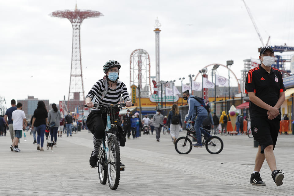 A woman rides her bicycle on the boardwalk at Coney Island during the current coronavirus outbreak, Sunday, May 24, 2020, in New York, during the Memorial Day weekend, which marks the traditional beginning of summer. (AP Photo/Kathy Willens)