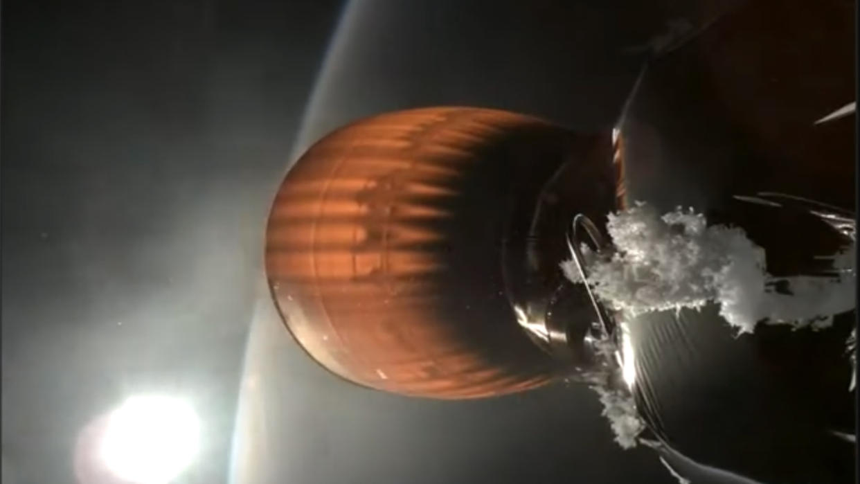  Closeup of a rocket engine in space, glowing orange, with earth in the background. near the engine is a strange buildup of white material. 