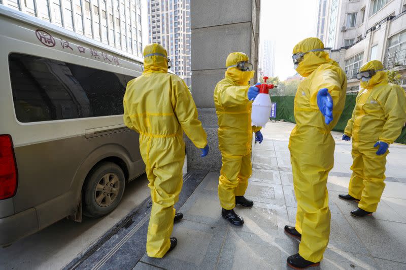 FILE PHOTO: Funeral parlour staff members in protective suits help a colleague with disinfection after they transferred a body at a hospital, following the outbreak of a new coronavirus in Wuhan