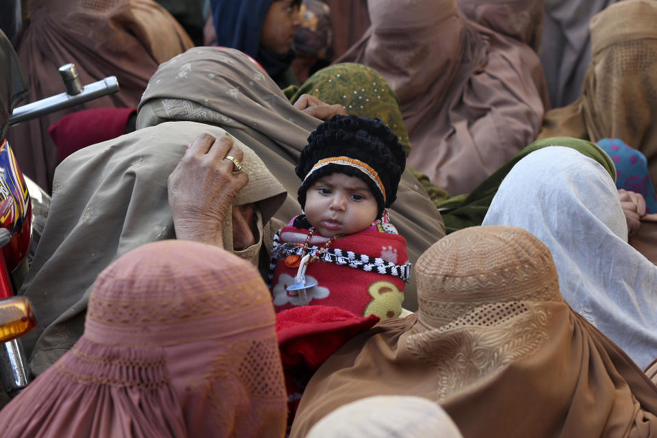 People stand in a long queue and wait to buy subsidized sacks of wheat flour in Peshawar, Pakistan, Monday, Jan. 9, 2023. People are suffering from recent price hike in wheat flour in Pakistan. (AP Photo/Muhammad Sajjad)