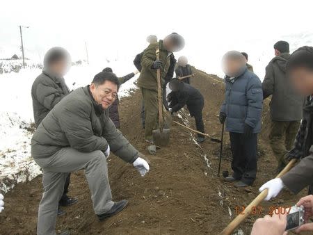 A photo provided by the Light Korean Presbyterian Church on March 5, 2015 shows Reverend Hyeon Soo Lim at an agricultural project in North Korea, with the faces of North Korean workers digitally blocked by the church to hide their identities. REUTERS/Light Presbyterian Church/Handout via Reuters