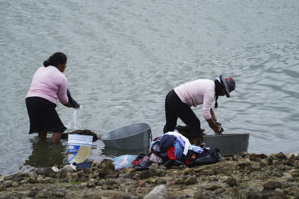 Locals wash clothes on the banks of the Villa Victoria reservoir in the the State of Mexico, Tuesday, Oct. 10, 2023. The capital’s reservoirs like Villa Victoria are running historically low following a “too dry” summer, according to official data, and as the rainy season draws to a close, water restrictions have already begun. (AP Photo/Marco Ugarte)