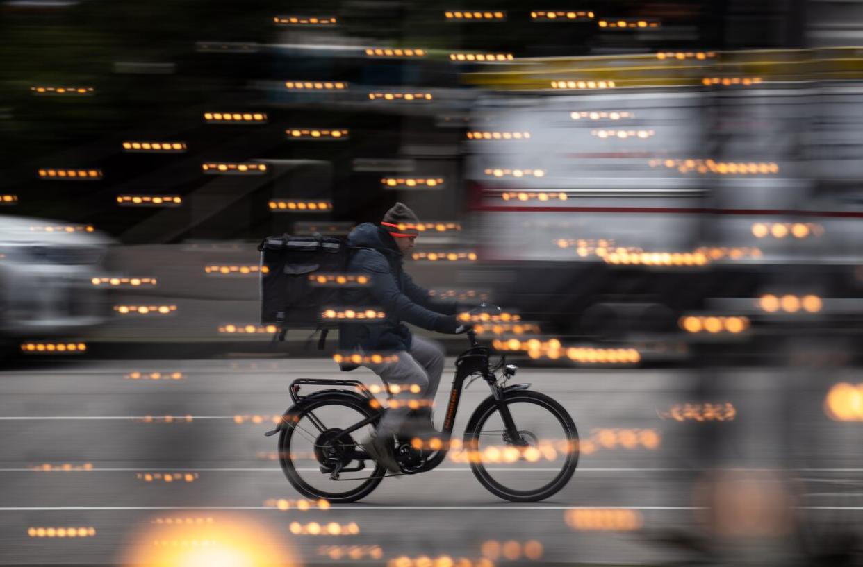 A food delivery worker rides a bike in downtown Vancouver in a 2021 file photo. (Darryl Dyck/The Canadian Press - image credit)