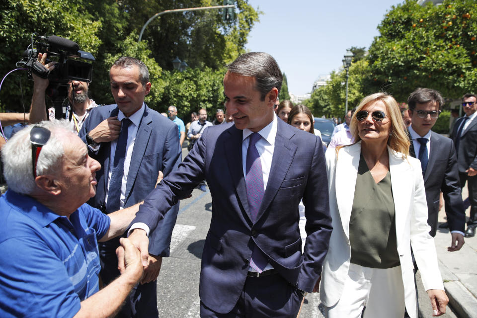Greek opposition New Democracy conservative party leader Kyriakos Mitsotakis centre, shakes hands with a supporter as he walks with his wife Mareva, right, in Athens, Monday, July 8, 2019. Mitsotakis was to be sworn in as Greece's new prime minister after a resounding win over left-wing Alexis Tsipras, who led the country through the tumultuous final years of its international bailouts. Mitsotakis' New Democracy party won 39.8% of the vote, giving him 158 seats in the 300-member parliament, a comfortable governing majority. (AP Photo/Thanassis Stavrakis)