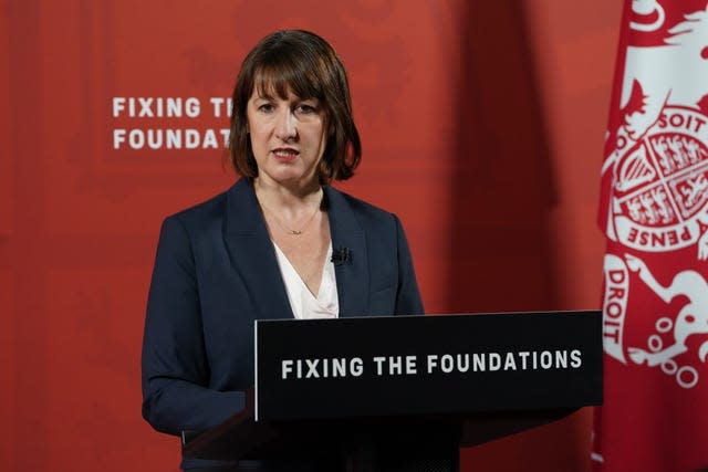 Chancellor Rachel Reeves stands behind a lectern bearing the slogan 