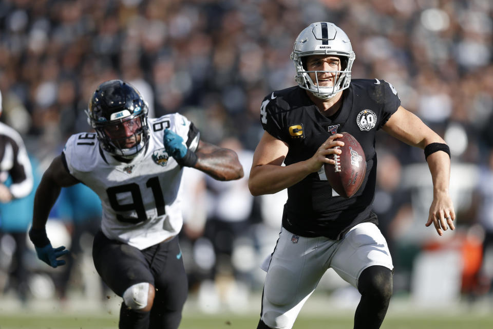 Oakland Raiders quarterback Derek Carr, right, runs with the ball away from Jacksonville Jaguars defensive end Yannick Ngakoue (91) during the second half of an NFL football game in Oakland, Calif., Sunday, Dec. 15, 2019. (AP Photo/D. Ross Cameron)